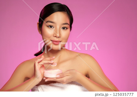 Model showcasing skincare product with pink background at studio setting during day Model showcasing skincare product with pink background at studio setting during day 125035777