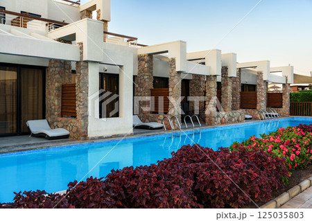 Luxury resort featuring a stunning blue pool and elegant architecture in a serene location during sunset 125035803