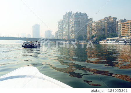 Beautiful skyline of Cairo reflected in the Nile with boats cruising along the calm waters in the early morning mist 125035861