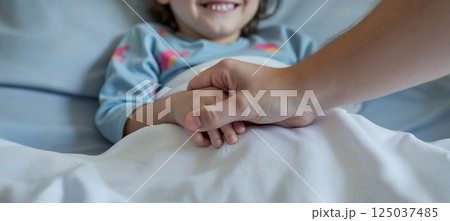 Touching hospital scene with a kid. The adult is holding her hand with care. Focus on hands 125037485