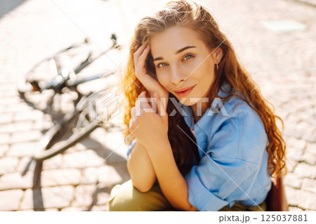 Portrait of smiling woman sitting next to bike on street city. Travel, weekend and lifestyle concept 125037881