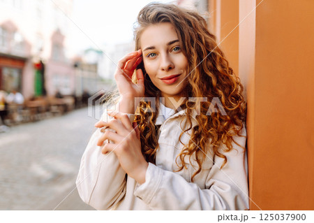 Optimistic woman with curly hair walking on the street city. Concept of lifestyle, fashion, travel. 125037900