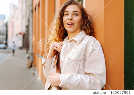 Optimistic woman with curly hair walking on the street city. Concept of lifestyle, fashion, travel. Optimistic woman with curly hair walking on the street city. Concept of lifestyle, fashion, travel. 125037901