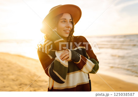 Portrait of a beautiful woman on the beach at sunset. Girl walks along the beach and enjoys weather 125038587