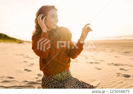 Portrait of a beautiful woman on the beach at sunset. Girl walks along the beach and enjoys weather 125038675