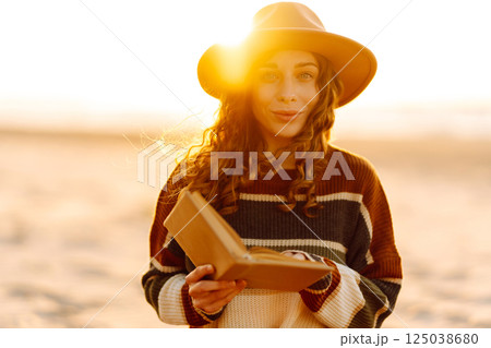 Romantic woman reading book sit on plaid have picnic outdoors on sea sand beach background 125038680