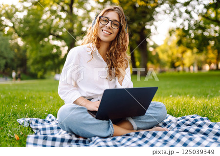 Young woman headphones sits listen to music use mobile cell phone. Concept for business, freelance. 125039349