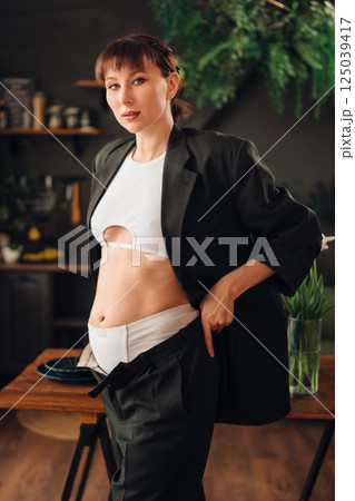 Young pregnant woman in stylish outfit poses in modern kitchen setting Young pregnant woman in stylish outfit poses in modern kitchen setting 125039417