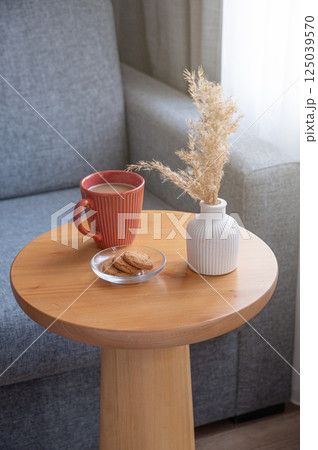 Cozy coffee setup with cookies and dried flowers on wooden table in living room. Cozy coffee setup with cookies and dried flowers on wooden table in living room. 125039570