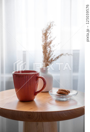 Cozy coffee setup with cookies and dried flowers on wooden table in living room. Cozy coffee setup with cookies and dried flowers on wooden table in living room. 125039576