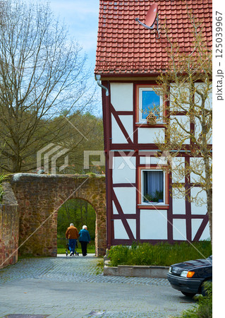 an elderly couple walks through the city and passes through an archway next to an old German house. High quality photo an elderly couple walks through the city and passes through an archway next to an old German house. High quality photo 125039967
