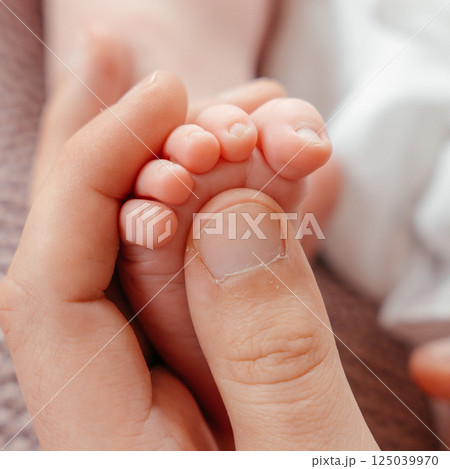 A newborn baby's feet in mom s hands close-up. High quality photo 125039970