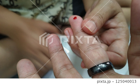 Man using lancet pen on finger to checking blood sugar 125040013