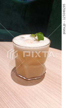 Creamy Iced Milk Tea with Mint Garnish in a Stylish Modern Setting on Wooden Table 125040295