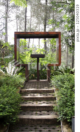 Scenic Outdoor Photo Spot with Wooden Frame Amidst Lush Greenery and Forest Background, Perfect for Couples to Relax and Enjoy Nature 125040319