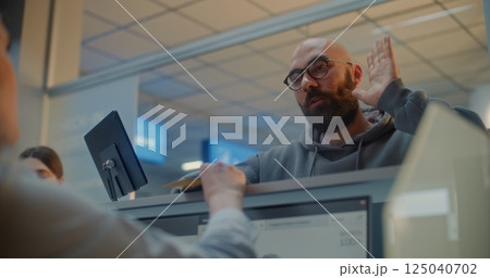 Female Airline Worker Checking Personal ID Data on Computer, Giving Passport and Airplane Ticket to Man 125040702