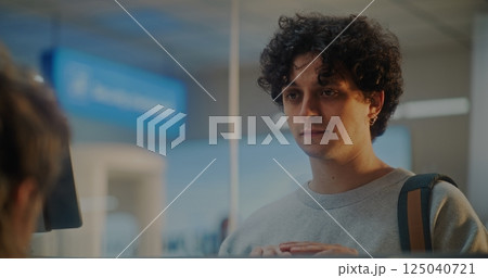 Airport Check-in Counter: Young Man Confirms Identity by Facial Recognition Scan Airport Check-in Counter: Young Man Confirms Identity by Facial Recognition Scan 125040721