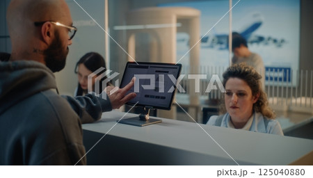 Airport Check-in Counter: Female Airline Worker Checking Tourist Personal ID Data for Flight 125040880