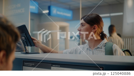 Female Airline Worker Checking Personal Data on Computer, Giving Documents and Boarding Pass to Woman 125040886