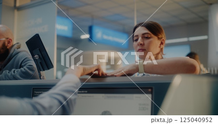 Female Airline Worker Checking Personal Data on Computer, Giving Documents and Boarding Pass to Woman 125040952