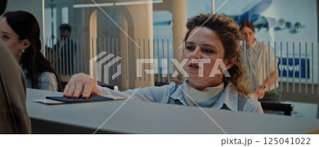Close Up of Female Airline Worker Checking Documents and Airplane Ticket of Passenger 125041022