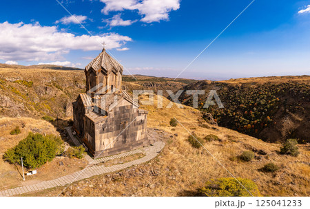 Aerial drone view to flag of Armenia and famous Vahramashen Church of the 11th century, near Amberd fortress in sunny summer day. Cliff with Arkashian River deep in canyon. Aragatsotn region, Armenia 125041233