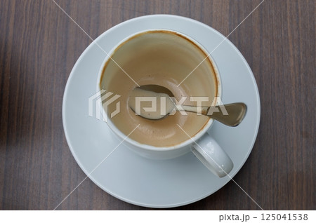 An empty coffee cup with a spoon resting inside, showcasing the remnants of a delightful beverage. 125041538
