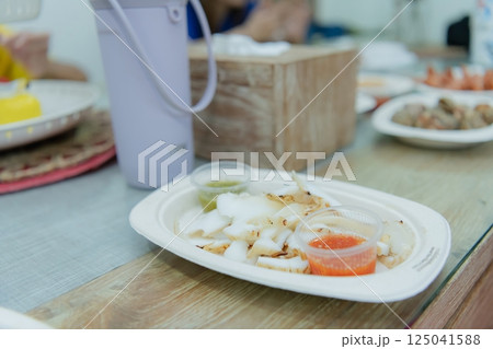 Delicious seafood dish served with sauces on a wooden table, showcasing a vibrant culinary experience. Delicious seafood dish served with sauces on a wooden table, showcasing a vibrant culinary experience. 125041588