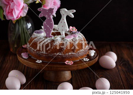 Traditional easter cakes with icing decorated with gingerbread cookies in shape of rabbits on dark wooden table Traditional easter cakes with icing decorated with gingerbread cookies in shape of rabbits on dark wooden table 125041950