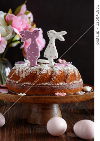 Traditional easter cakes with icing decorated with gingerbread cookies in shape of rabbits on dark wooden table 125041951