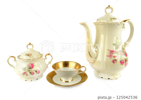 Elegant vintage porcelain coffee pot, porcelain sugar bowl , porcelain cup and saucers isolated on white background. Elegant vintage porcelain coffee pot, porcelain sugar bowl , porcelain cup and saucers isolated on white background. 125042536
