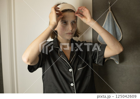 A woman removes a textile cosmetic mask from her forehead 125042609
