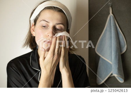 woman in the bathroom wiping her face with a paper towel woman in the bathroom wiping her face with a paper towel 125042613