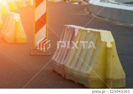 Red, white plastic safety barriers along road. Ensuring road safety with visible barriers. Effective safety measures for roadside work. 125043163
