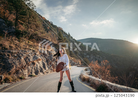 Woman road mountain. A woman in a white sweater, black boots and a hat walks along a winding alpine path between the mountains at sunset in late summer. The concept of travel. Woman road mountain. A woman in a white sweater, black boots and a hat walks along a winding alpine path between the mountains at sunset in late summer. The concept of travel. 125043190