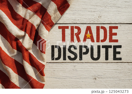 TRADE DISPUTE painted on wood with fabric resembling USA flag, symbolizing commercial conflict, tensions and international economic confrontation 125043273