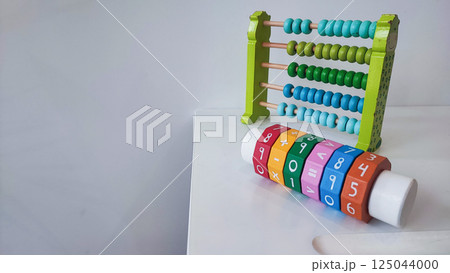 Children's wooden construction set, abacus, on a white table. Concept of children's development, montesori Children's wooden construction set, abacus, on a white table. Concept of children's development, montesori 125044000