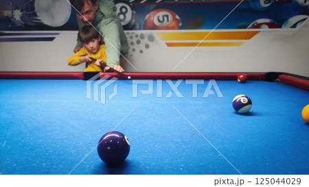 The young father learns the son to play billiards. concept of father-son todler pastime 125044029