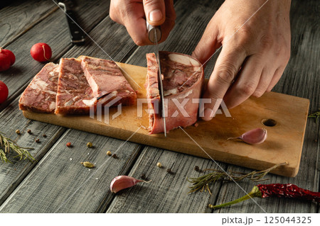 Hands skillfully cut fresh meat on a wooden board surrounded by garlic, spices, and radishes. This activity takes place in a cozy kitchen atmosphere, showcasing culinary expertise. Hands skillfully cut fresh meat on a wooden board surrounded by garlic, spices, and radishes. This activity takes place in a cozy kitchen atmosphere, showcasing culinary expertise. 125044325