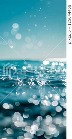Sunny day bokeh on water: Blue sky over a turquoise body of water, with the light reflecting and creating a bokeh effect. 125044458