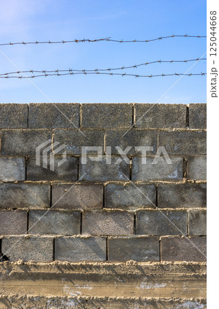 Barbed Wire Above Concrete Block Wall 125044668