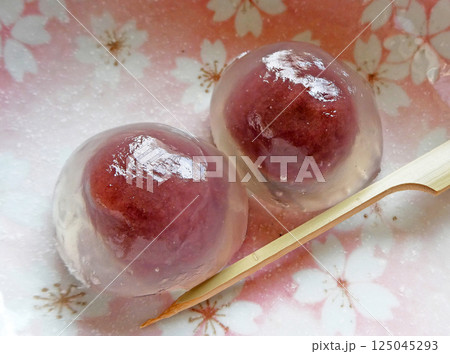 ピンクの桜模様の器で撮影した、あんこが透き通るくず餅の写真 125045293