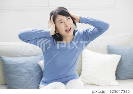 体調不良やショックで頭を抱えるミドル女性 体調不良やショックで頭を抱えるミドル女性 125047530