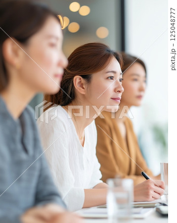 斜めアングルで捉えた女性社員3名のオフィスミーティング風景 125048777