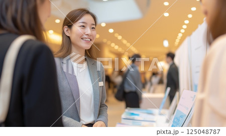 展示会で来場者と会話をする女性社員のビジネスシーン 125048787
