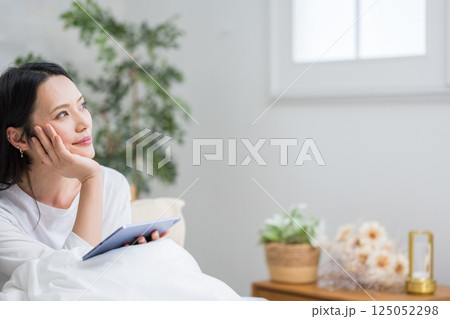 室内でタブレットを操作する女性｜読書勉強｜健康的な暮らしイメージ｜ウェルビー女子｜ウェルビーイング 125052298