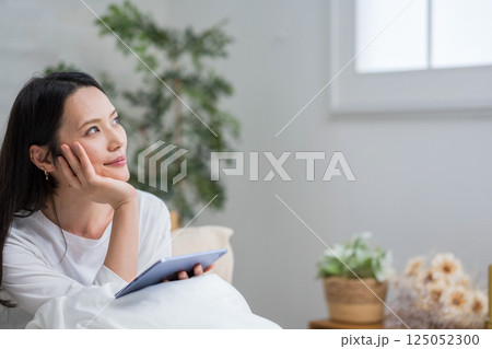 室内でタブレットを操作する女性｜読書勉強｜健康的な暮らしイメージ｜ウェルビー女子｜ウェルビーイング 125052300