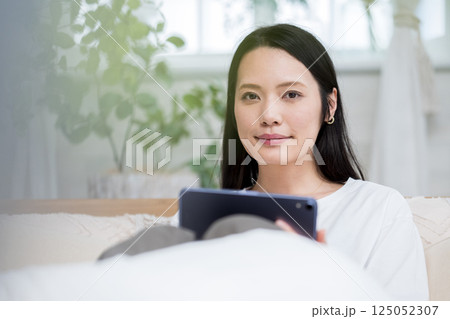 ベッドでタブレットを操作する女性｜読書勉強｜健康的な暮らしイメージ｜ウェルビー女子｜ウェルビーイング 125052307