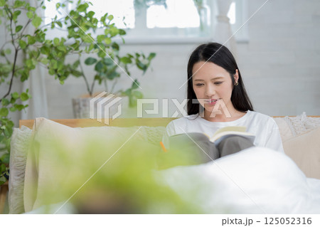 ベッドで読書をするきれいな女性｜勉強｜趣味｜健康的な暮らしイメージ｜ウェルビー女子｜ウェルビーイング 125052316