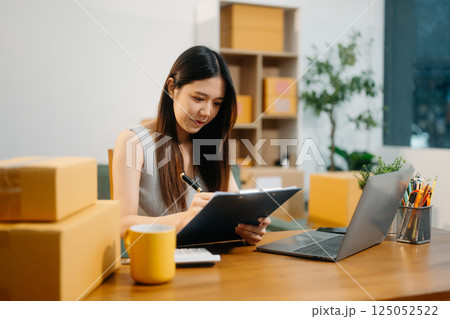 Young business owner woman prepare parcel box and standing check online orders for deliver Young business owner woman prepare parcel box and standing check online orders for deliver 125052522
